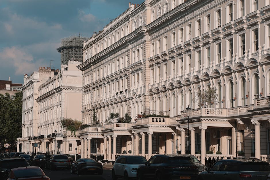 The image shows a city street scene in Westminster with several multi-storey buildings featuring brick and ornate facade designs, typical of the Belgravia area. A light blue moving van belonging to We